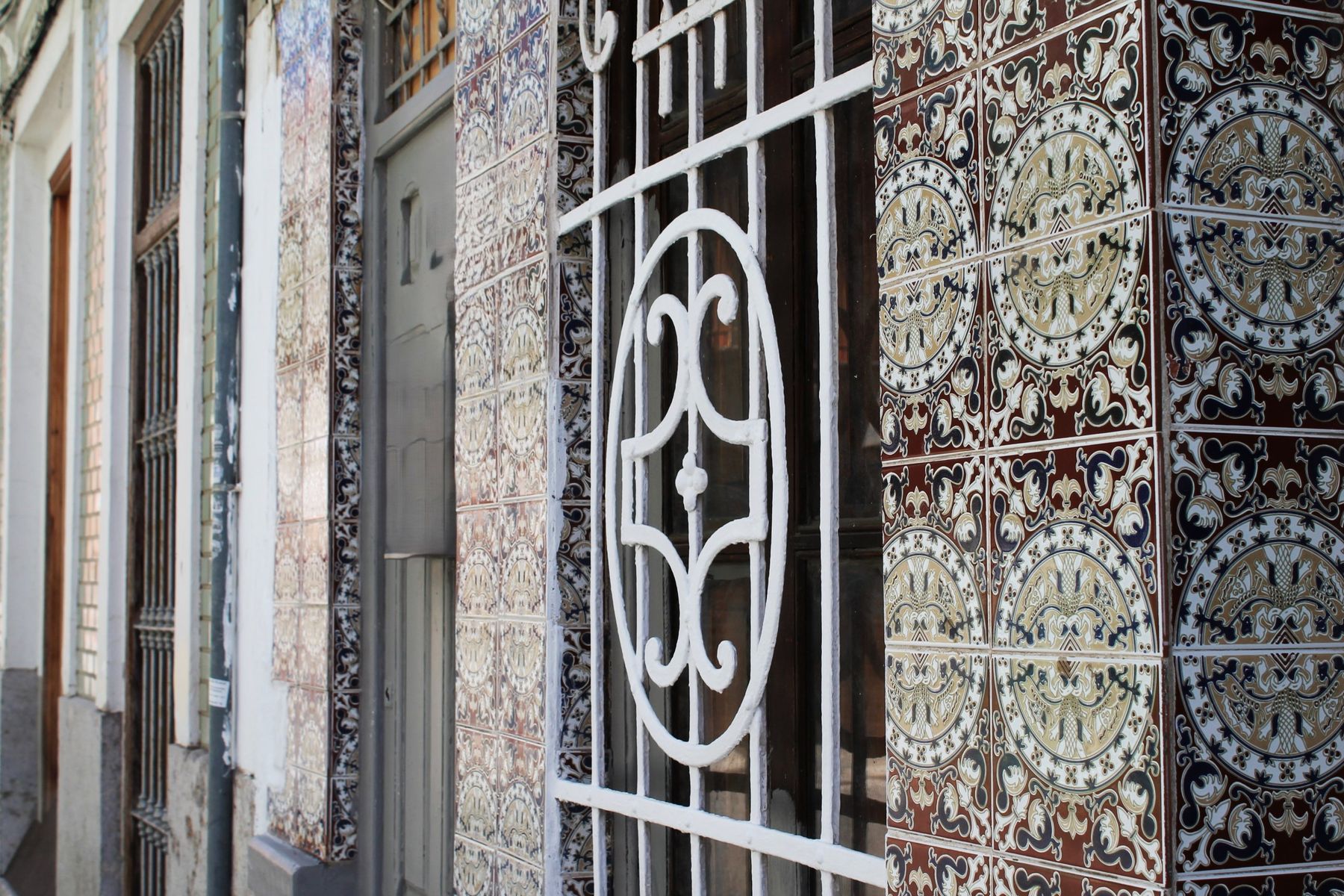 Detalle de azulejos valencianos y reja blanca en una fachada de El Cabanyal
